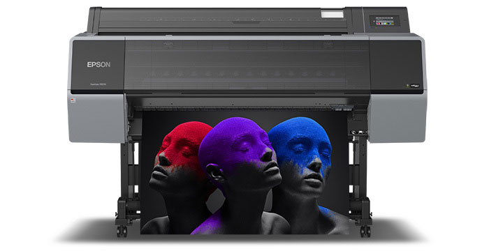Three mannequin heads in red, purple, and blue inside a printer.